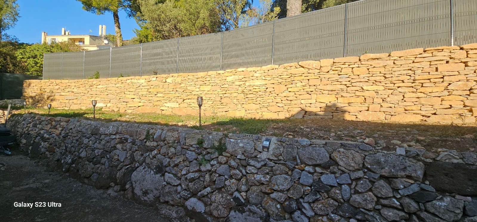 création d un muret de soutenement en pierres séches avec une clôture grillage et pose occultant