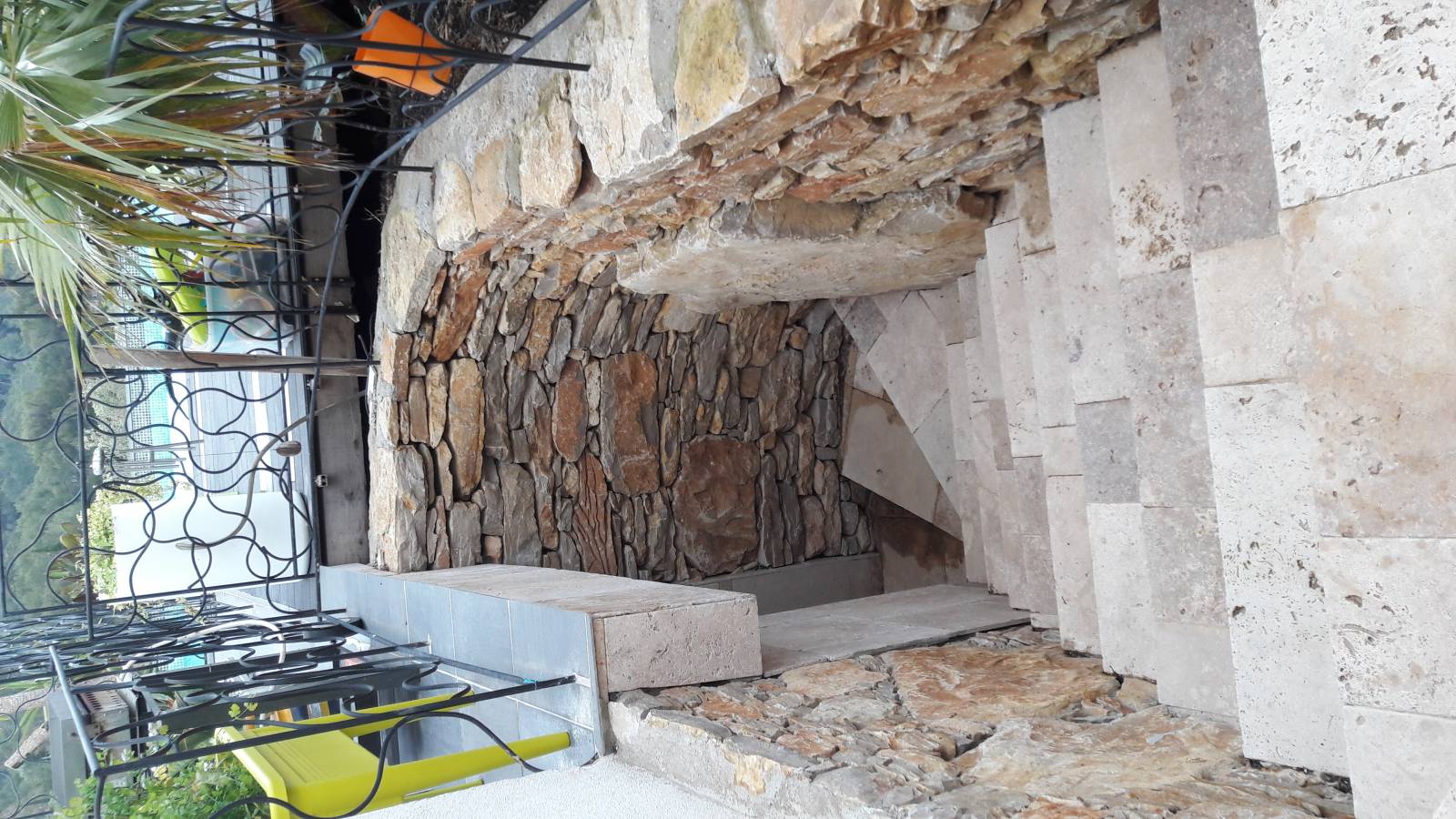 Pose d'un grande pierre plate dans un muret en petites pierres