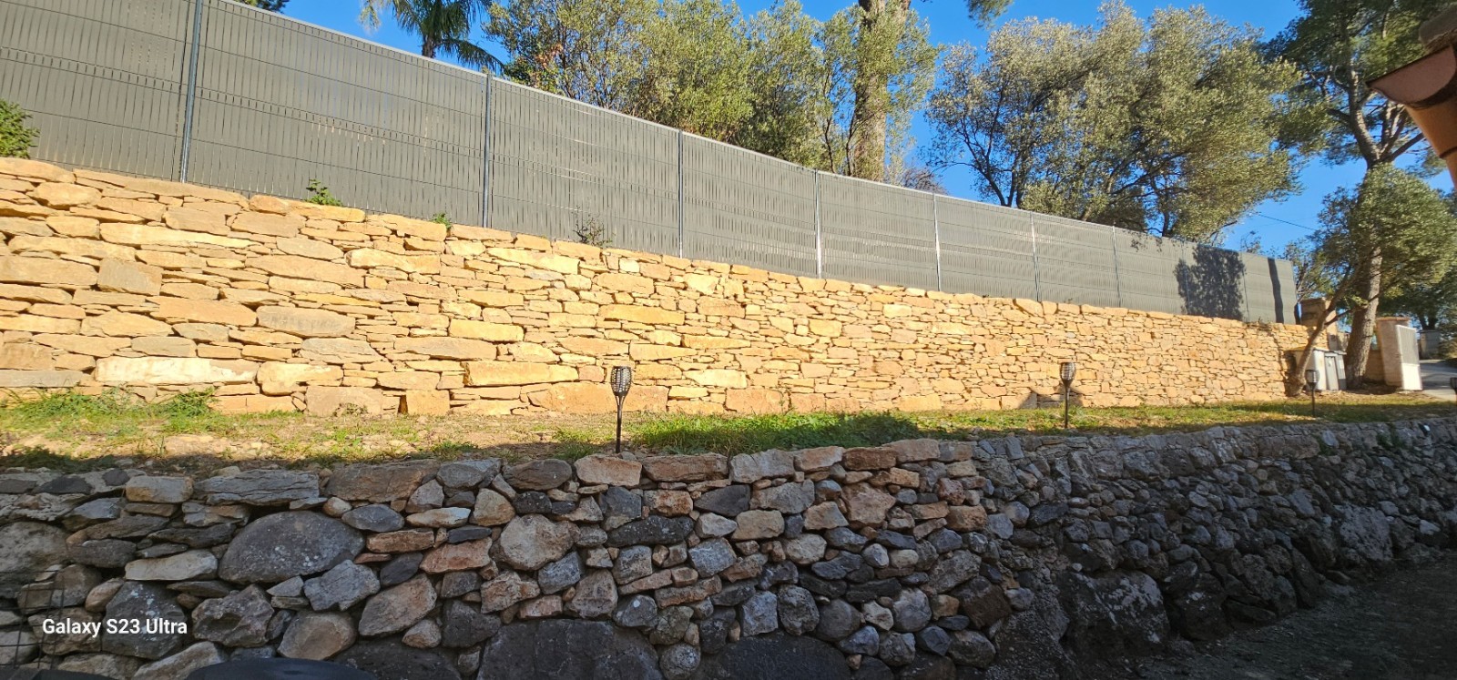 création d un muret de soutenement en pierres séches avec une clôture grillage et pose occultant