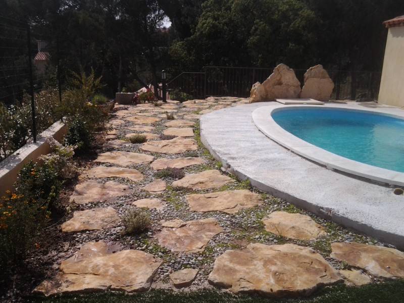 pierres de dallage autour d' une piscine avec plantations de plantes  rampantes à bormes les mimosas dans le var