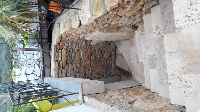 Pose d'un grande pierre plate dans un muret en petites pierres