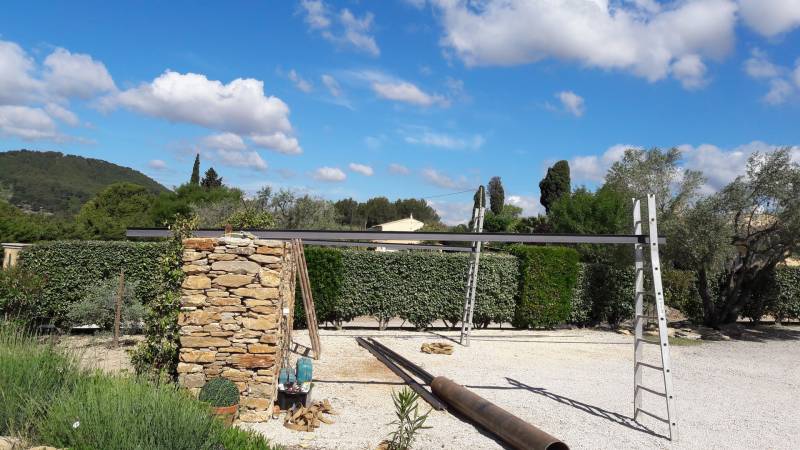 Pose d' une pergolas artisanale sur un mur en pierres dans le var aux Beausset