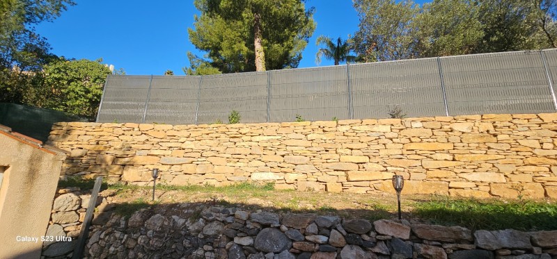 création d un muret de soutenement en pierres séches avec une clôture grillage et pose occultant